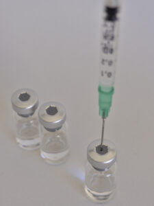 vaccine bottles and syringe with injection fluid and aluminum caps_green syringe